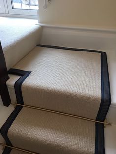 the carpeted stairs are lined with black and white rugs in front of a window