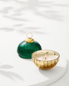 a green glass candle sitting next to a gold bowl