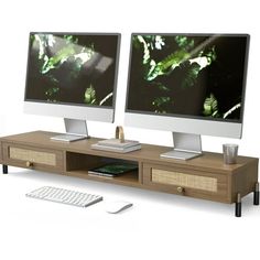 two computer monitors sitting on top of a wooden desk