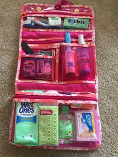 an open pink suitcase on the floor with toiletries and hand sanitizers in it