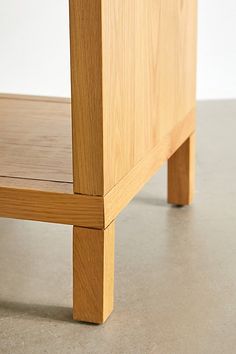 a wooden bed frame sitting on top of a cement floor next to a white wall