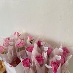 a bunch of pink roses sitting in a white box on a table with paper hearts attached to them