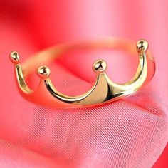 a gold crown ring on top of a pink cloth with red fabric in the background