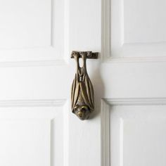 a door handle with a bat shaped object on it's side hanging from a white door