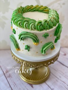 a white cake with green frosting sitting on top of a gold plated stand