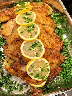 chicken with lemons and parsley on a platter ready to be served in the oven