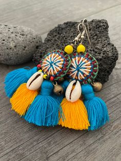 Unique fun and colorful earrings. Made with yellow and blue tassels and a beautiful round center piece made with different fabrics and strings, the earrings are adorned with beads, brass bells and shells. This pair will rock your outfit. Fun and easy to wear as they are super light. The earrings are 6cm- 2.40inch long 5.3cm- 2.10inch wide This timeless pair will brighten up your days! To see more unique and fun colorful tassel earrings, click the link below https://www.etsy.com/shop/AkashiJewelr Yellow Bohemian Earrings With Latkans, Bohemian Yellow Earrings With Latkans, Yellow Bohemian Tassel Earrings For Beach, Yellow Tassel Earrings For Festival, Handmade Blue Bohemian Tassel Earrings, Bohemian Beaded Earrings With Latkans For Beach, Bohemian Blue Fringe Tassel Earrings, Blue Bohemian Tassel Earrings For Summer, Bohemian Blue Tassel Earrings For Summer