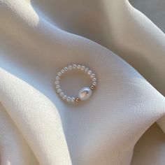 Delicate elastic fresh water pearl ring with 14kt gold filled beads. Carefully selected and high quality lustrous pearls make the ring truly beautiful and one of a kind. The delicate and minimalist design of the ring goes well with both casual and sophisticated looks. Size of the small pearl beads is approx. 2-2.5mm Size of the center large bead: 6x8mm Size of the gold filled bead: 2.5mm Follow us on INSTAGRAM: @soellejewelry Tag us on social media: #soellejewelry Packed with care and ready to s Pearl Ring Handmade, Diy Beads Ring Ideas, Pearl Beaded Ring, Ring Ideas Diy Bead, Pearl Rings Aesthetic, Ring Designs Beads, Elegant Beaded Wedding Rings, Elegant Beaded Rings For Anniversary, Yellow Gold Pearl Ring With Pearl Charm