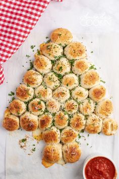 a christmas tree made out of rolls and sauce on a white tablecloth with a red checkered napkin