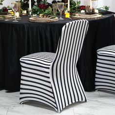 two black and white striped chairs sitting in front of a table with candles on it