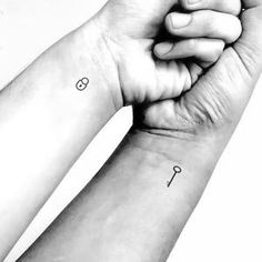 two hands holding each other with small tattoos on their wrist and one has an anchor