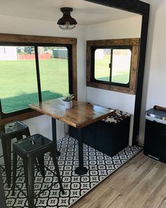 the inside of a mobile home with windows and a table in front of two stools