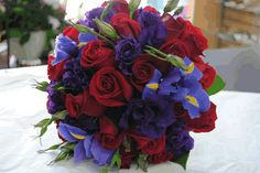 a bridal bouquet with red, purple and blue flowers on a white table cloth