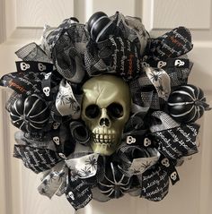 a wreath decorated with black and white ribbons, skulls and bones is hanging on the front door