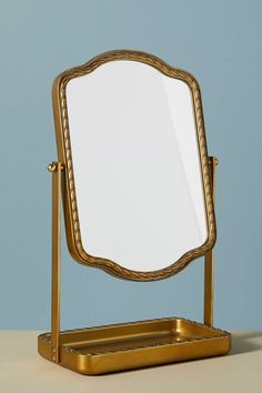 a mirror sitting on top of a metal stand next to a blue wall in the background