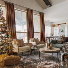 a living room filled with furniture and a christmas tree in front of two large windows