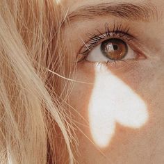 a woman's face with the shadow of a heart on her cheek and long eyelashes