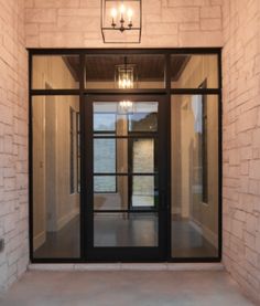 an open door with two lights hanging from it's side and brick wall in the background