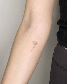 a woman's arm with a single flower tattoo on the left side of her arm