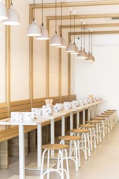 a long table with many chairs and lights hanging from the ceiling