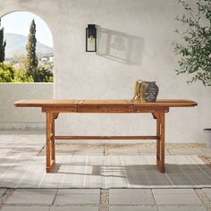 a wooden table sitting on top of a tiled floor next to a potted plant