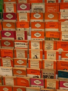 many books stacked on top of each other in orange and green boxes with white labels