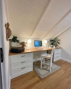 there is a desk with a computer on it in the corner of this attic room