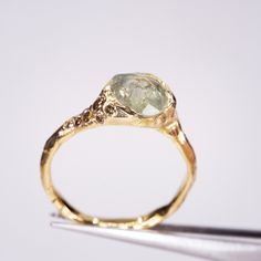 a yellow gold ring with a green diamond