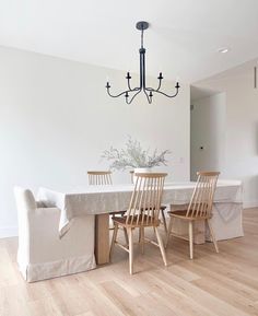 a dining room table with four chairs and a chandelier hanging from the ceiling