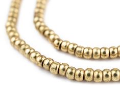 a gold beaded necklace on a white background