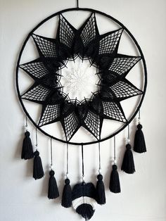 a black and white dream catcher with tassels hanging from it