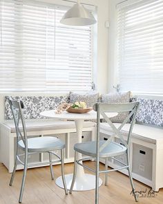 a kitchen table with two chairs and a bench in front of the window covered by blinds