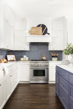 a kitchen with white cabinets and blue backsplash