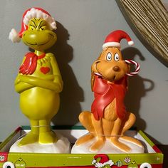 the grinch and cat in the hat figurines are sitting on top of each other