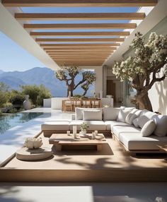 an outdoor living area with white couches and wooden tables next to a swimming pool