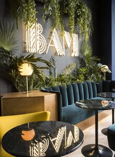 the interior of a restaurant with green plants on the wall and blue velvet seating area