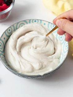 a person is dipping some fruit into a bowl with yogurt on the side