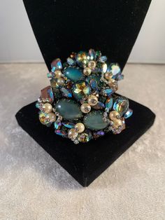 "This is an extremely rare and beautiful SPARKLING Hobé brooch and bracelet demi parure fully encrusted in large and small saphiret glass cabochons/stones that exhibit turquoise-pink-brown tones. All pieces are accented with rhinestone topped pearls and small green and orange round rhinestones and several blue-green metallic finished navettes! The other quite unique addition are the small arrow-shaped clusters of tiny AB rhinestones surrounding the pearls that move freely. It really is such a beautiful set, and must be seen in person to appreciate - I tried to capture the beauty of the saphiret stones which is difficult to do in a picture. The glass was made in the first half of the century by adding gold to sapphire blue glass (the earlier the piece the pinker tone of the stone), creating Multicolor Brooch Jewelry For Evening, Multicolor Brooch For Evening Wear, Unique Evening Bracelet Jewelry, Unique Jeweled Bracelets For Formal Occasions, Multicolor Party Jewelry With Brooch, Unique Multicolor Jewelry Brooch, Unique Multicolor Jewelry With Brooch, Multicolor Wedding Brooch Jewelry, Unique Multicolor Evening Jewelry