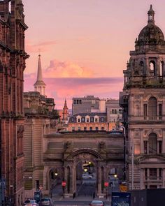 an old city street with tall buildings and cars driving down it's sides at sunset