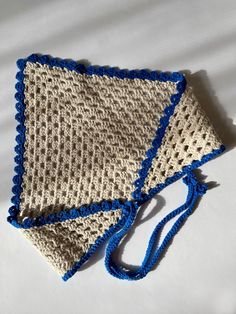 two pieces of crocheted cloth with blue trims on top of white sheets