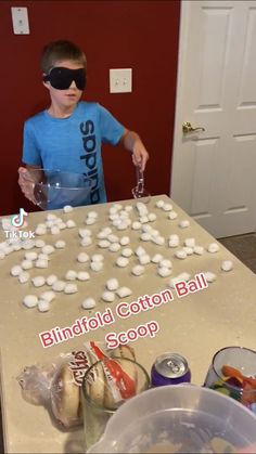 a young boy wearing blindfold cotton balls at a table