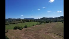 an aerial view of a large field with mountains in the distance and blue skies above