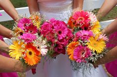 the bridesmaids are holding their colorful bouquets