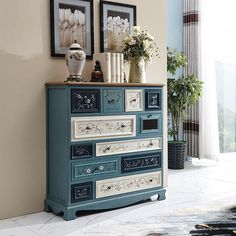 a blue dresser with flowers and pictures on the wall