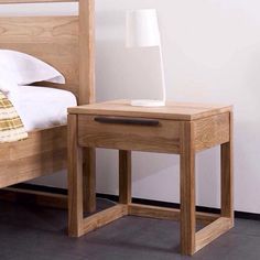 a nightstand with a lamp on top of it next to a bed