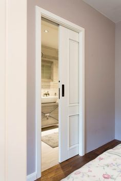 an open door leading to a bedroom with a bed in the corner and a bathroom behind it