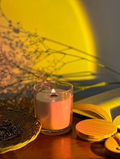 a candle sitting on top of a wooden table next to an open book and plate