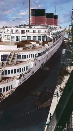 a large cruise ship docked at the dock with other ships in the water behind it