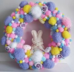 a colorful wreath with pom poms and stuffed animals