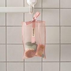 a pink bag hanging from the side of a bathroom wall next to a toilet paper dispenser